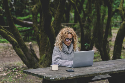 Portrait of young woman using laptop at park