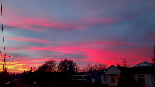 Silhouette houses against dramatic sky during sunset