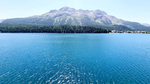 Scenic view of sea and mountains against blue sky