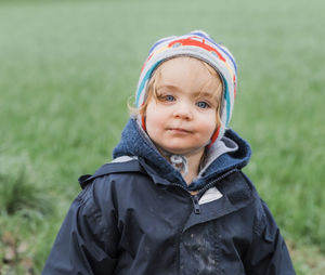 Portrait of cute girl sitting on field during winter