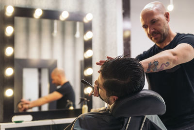 Barber shaving beard in salon