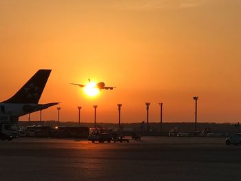 Airplane on runway against sky during sunset