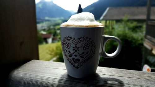 Close-up of heart shape on coffee cup at window