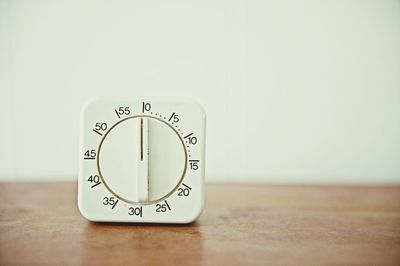 Close-up of oven knob on table against wall