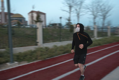 Full length of man wearing mask running in park