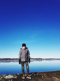 Full length of boy standing on pier against sky