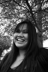 Portrait of young woman standing against trees