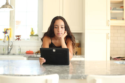 Portrait of smiling young woman using phone at home