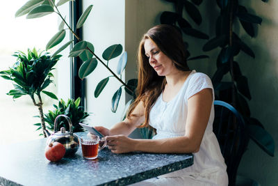 Young woman sitting on table at home