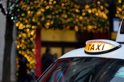 Close-up of taxi against illuminated defocused light in city