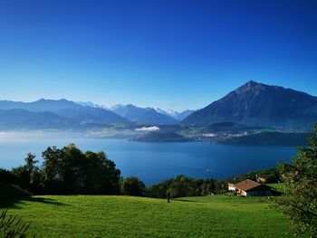 Scenic view of house and mountains against blue sky