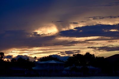 Silhouette houses against sky during sunset