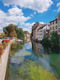 Canal amidst buildings in city against sky