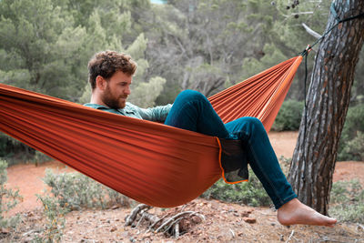 Man sitting on hammock in forest