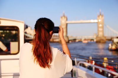 Rear view of woman on bridge against sky in city