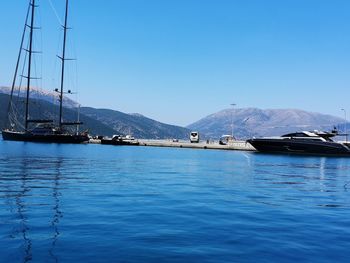 Sailboats in sea against clear blue sky