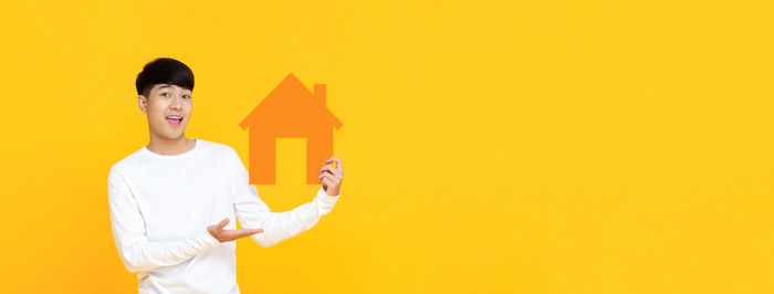 Full length of man standing against yellow wall