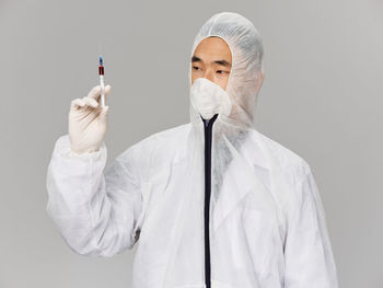 Doctor holding syringe against white background