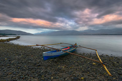 Fishing boat moored on lake against sky