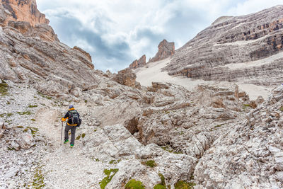 Rear view of person on rocks in mountains against sky