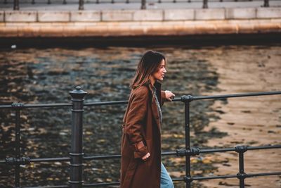 Side view of young woman standing against buildings