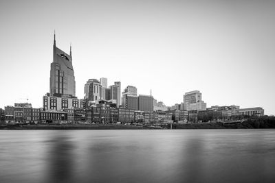 River by buildings against clear sky in city