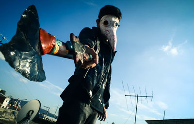 Low angle view of man standing against blue sky