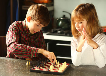 Children playing chess at home kitchen