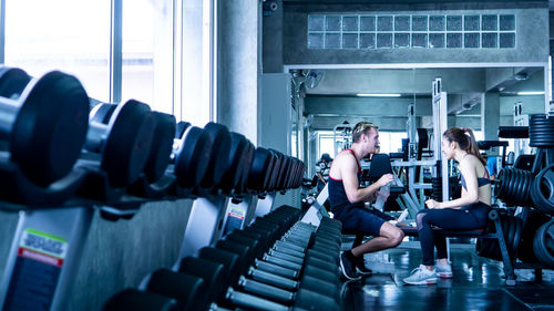 Side view full length of friends sitting at gym