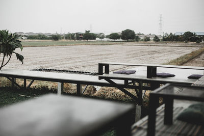 Empty bench on field against clear sky