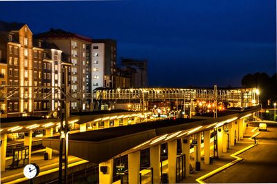 Illuminated city against blue sky at night