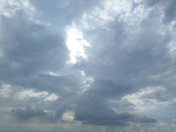 Low angle view of sunlight streaming through clouds