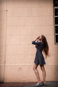 Full length of woman standing against wall