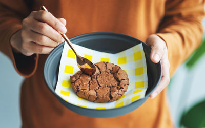 Closeup image of a woman eating delicious chocolate cookie with spoon