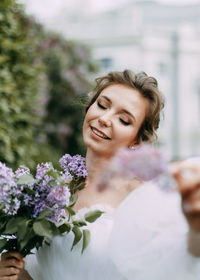 A beautiful delicate young woman bride in a wedding dress walks in a blooming spring outdoor park