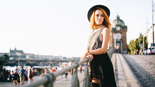 Woman standing by railing against sky
