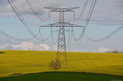 Electricity pylon on field against sky