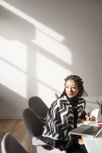 Thoughtful businesswoman sitting on chair in creative office