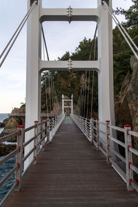 Bridge leading towards footbridge against sky