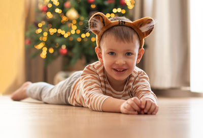 Portrait of cute boy lying on floor at home