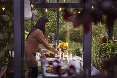Woman preparing table in greenhouse