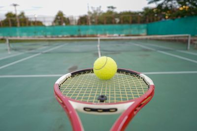 Close-up of tennis ball and racket at court