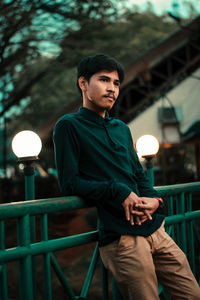 Young man looking away while standing by railing