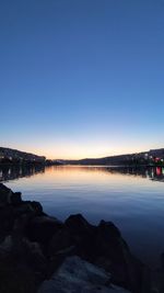 Scenic view of lake against clear sky at sunset