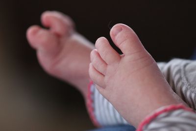 Low section of baby feet against black background