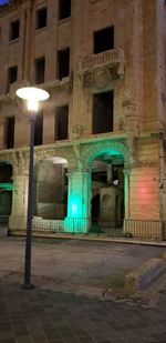 Illuminated street light by building at night