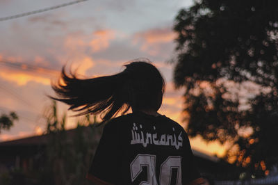 Rear view of silhouette woman standing against sky during sunset