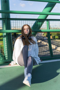 Portrait of woman sitting on railing