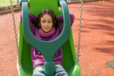 Girl playing on swing at playground