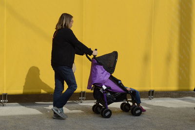 Side view of boy walking with yellow umbrella